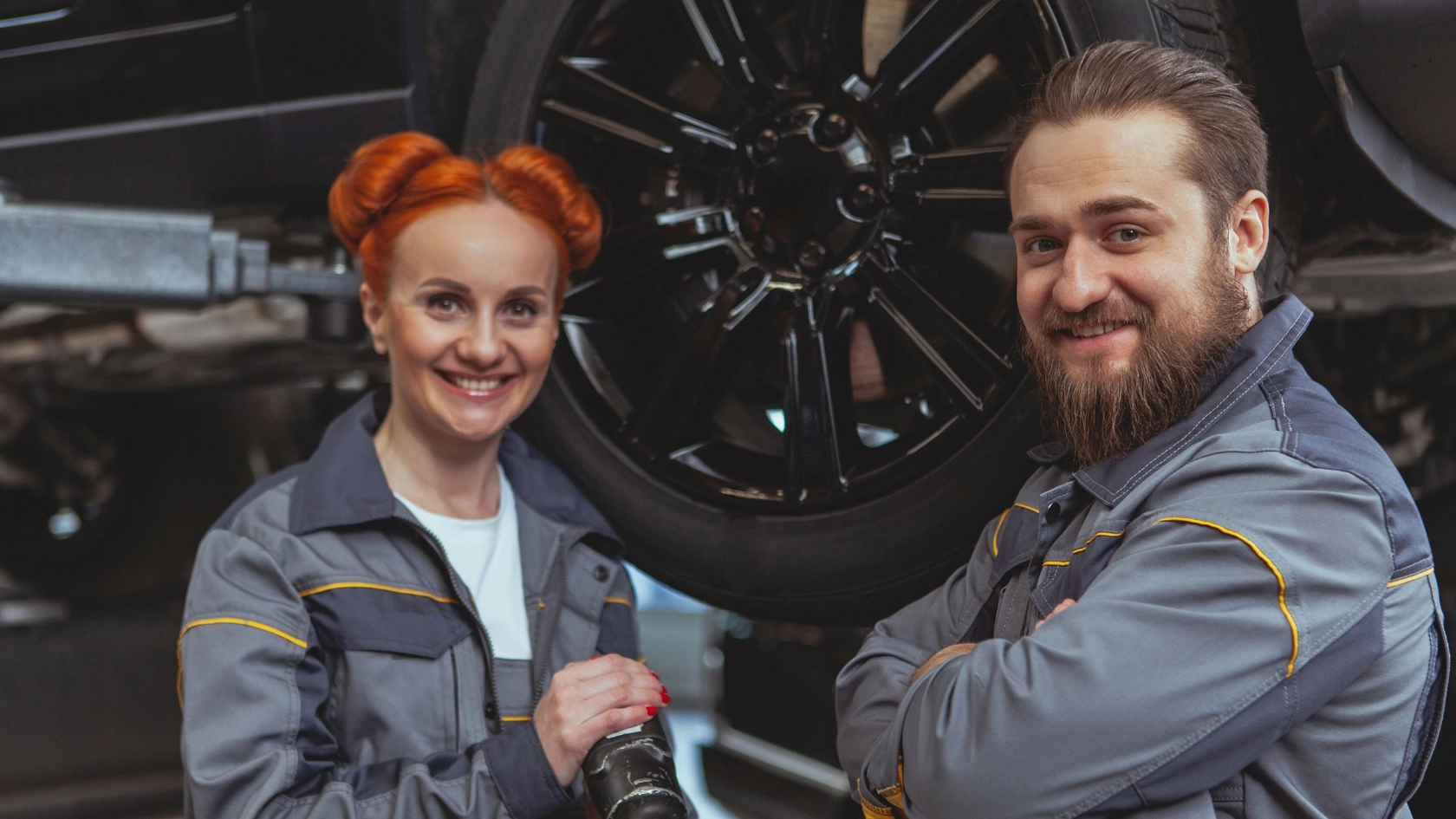 Eine Kfz-Mechanikerin und ein Mechaniker vor einem Auto