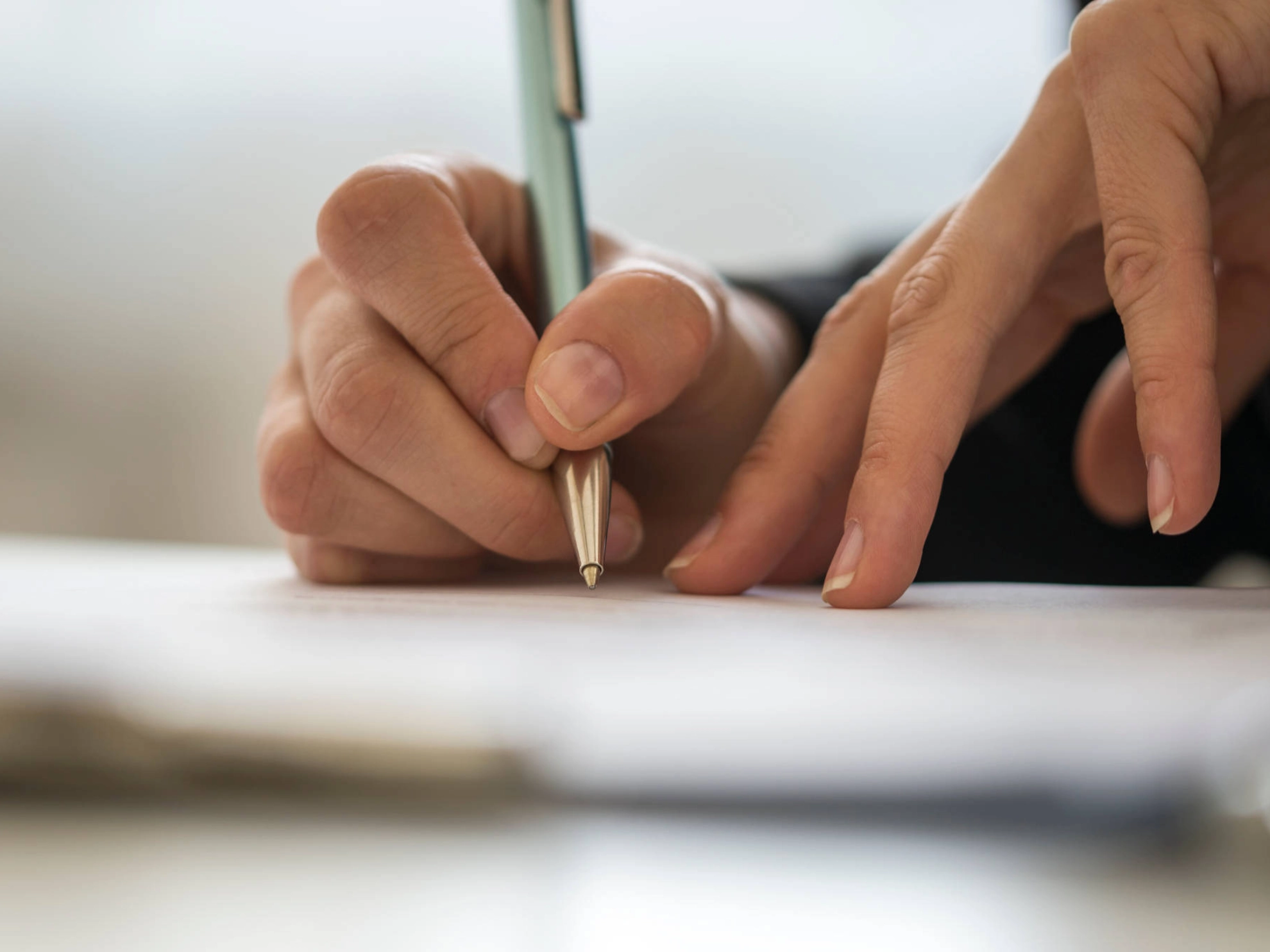 Jemand schreibt etwas auf ein Stück Papier.