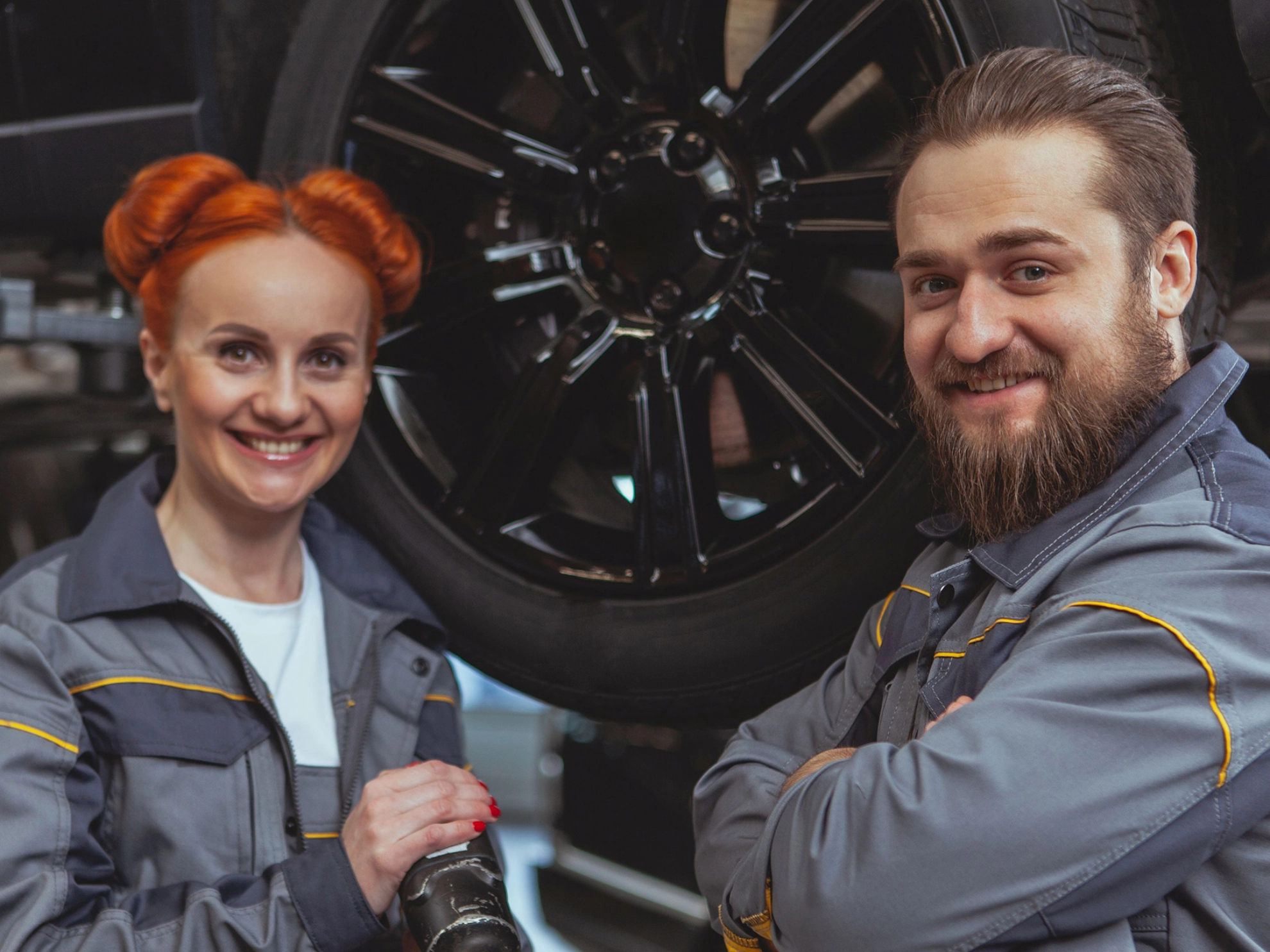 Eine Kfz-Mechanikerin und ein Mechaniker vor einem Auto