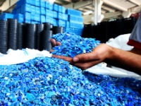 Eine Hand hält blaues Kunststoffgranulat.