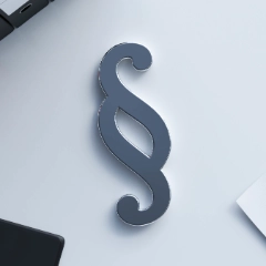 Ein großes Paragraphensymbol liegt auf einem weißen Schreibtisch neben Stiften, Papier und Ordnern