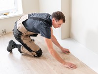 Ein Bodenleger verlegt Laminat