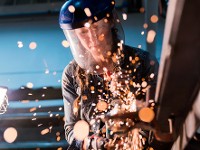 Eine Handwerkerin arbeitet mit einem Winkelschleifer in einer Werkstatt