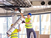 Beschäftigte richten eine Lüftungsanlage in einem Neubau ein