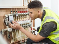 Auszubildender reguliert Messtechnik an Heizungsanlage